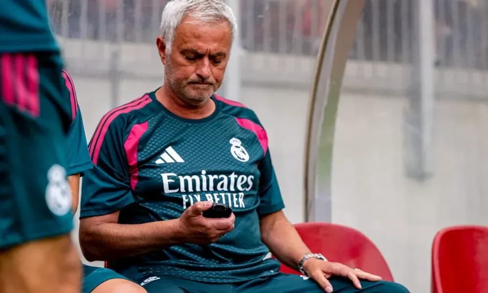 Entrenador de Real Madrid revisando su teléfono en el banquillo