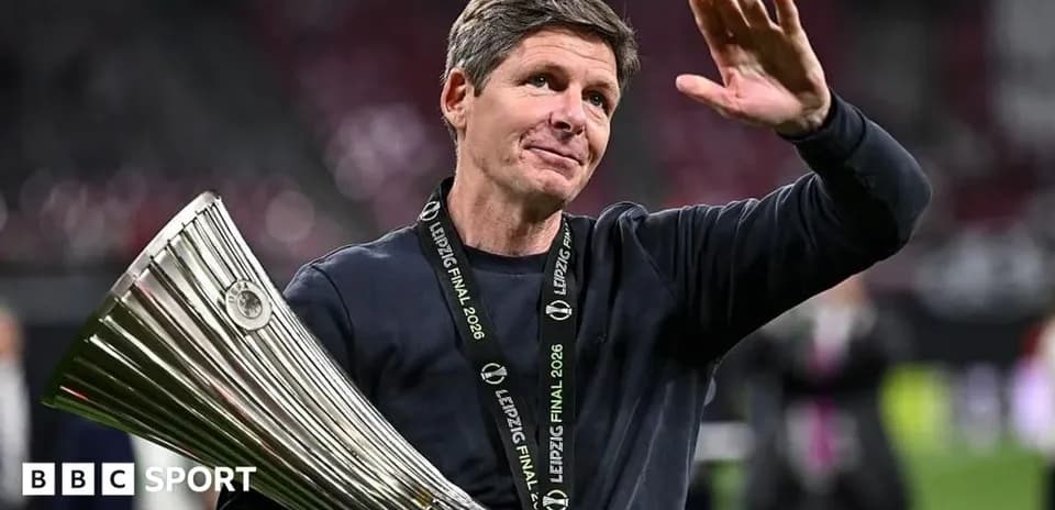 Entrenador sosteniendo trofeo y saludando al público