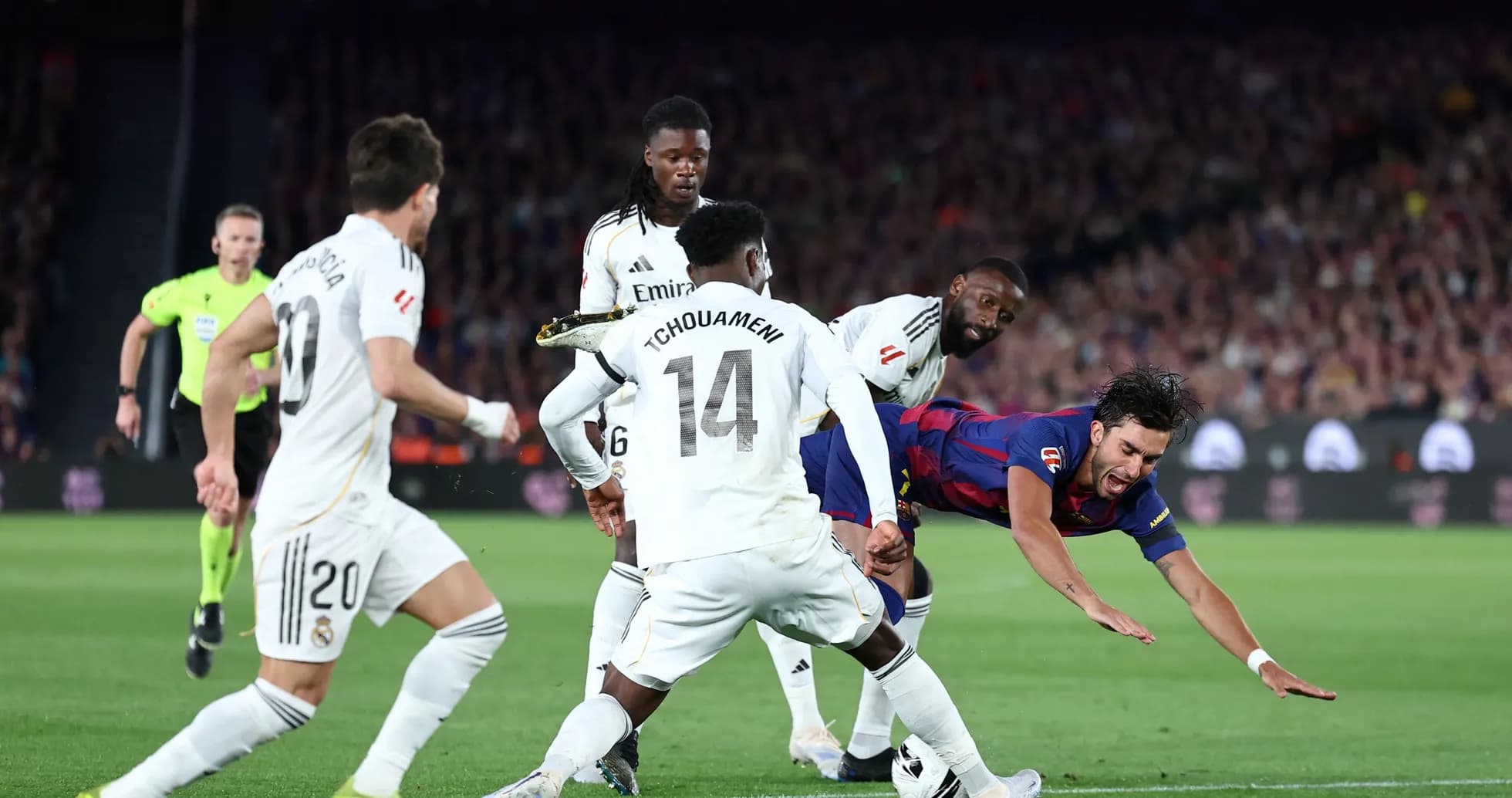 Jugador de Barcelona cayendo mientras es tackleado por Real Madrid