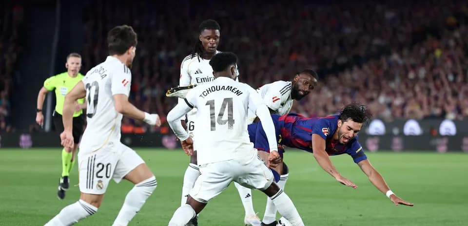 Jugador de Barcelona cayendo mientras es tackleado por Real Madrid