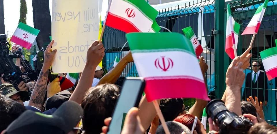 Multitud con banderas de Irán y pancarta en protesta