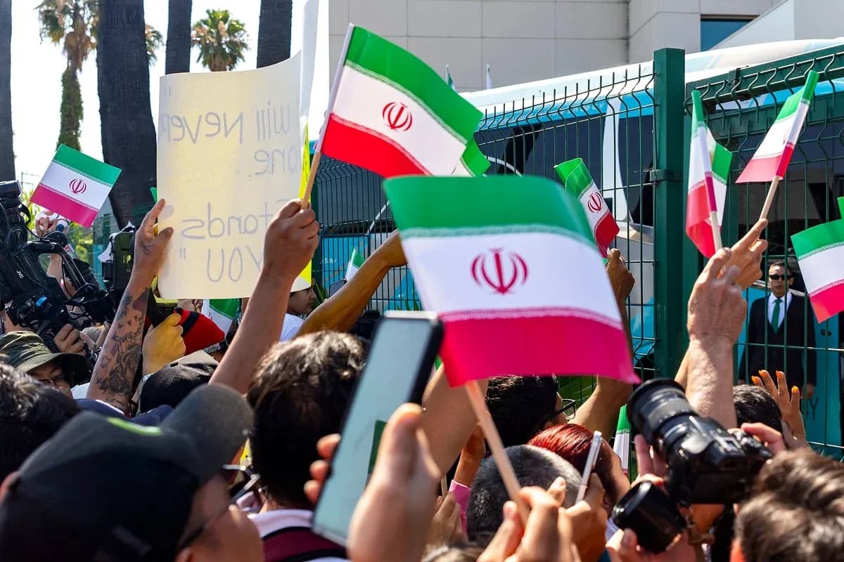 Multitud con banderas de Irán y pancarta en protesta