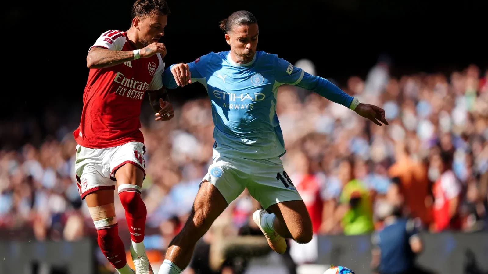 Jugadores de Arsenal y Manchester City luchando por el balón