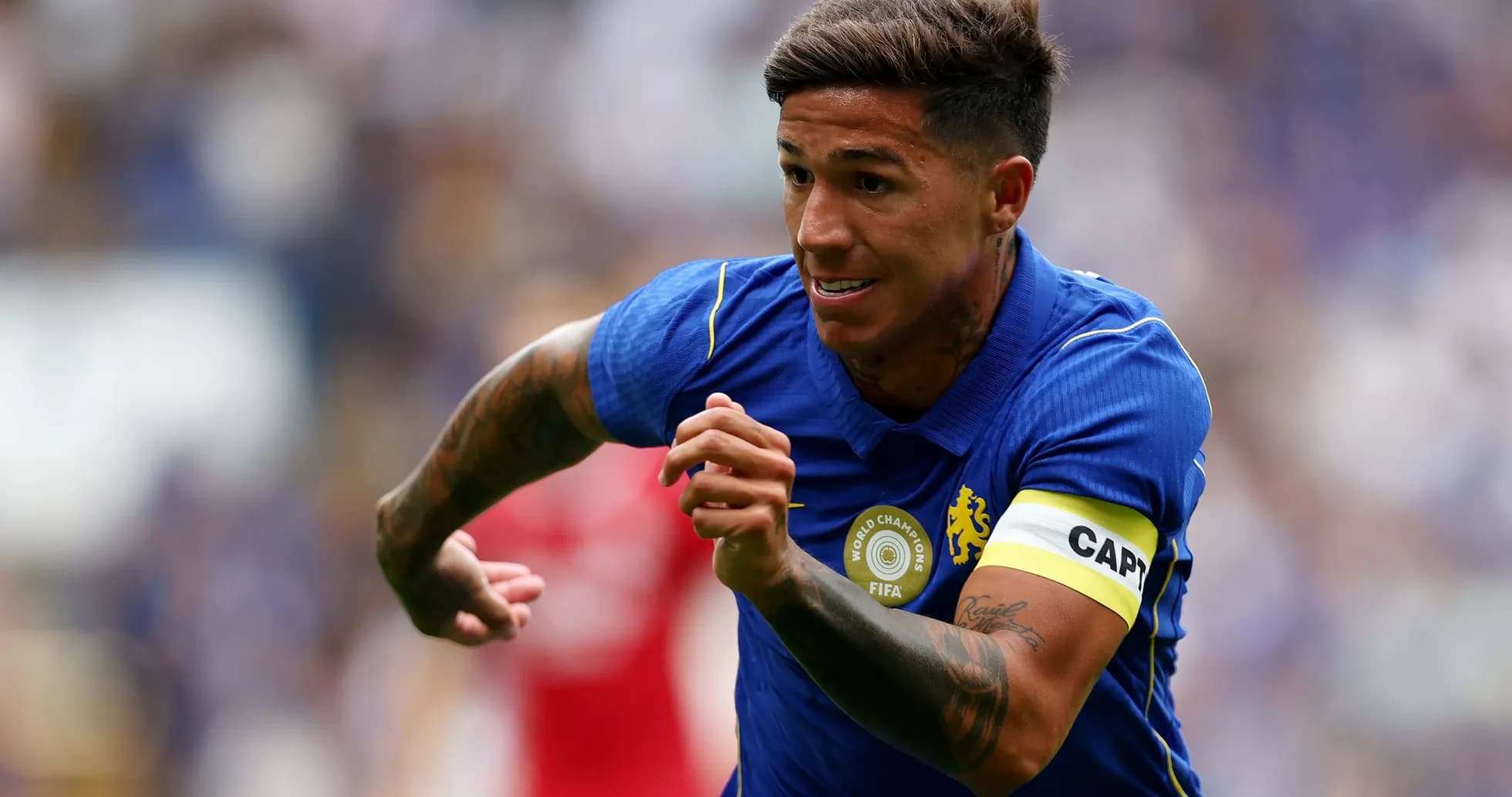Jugador corriendo con camiseta de Chelsea y cinta de capitán