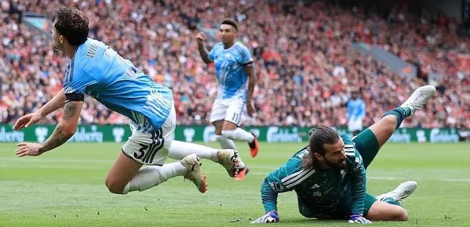 Jugador caído mientras el portero detiene el balón
