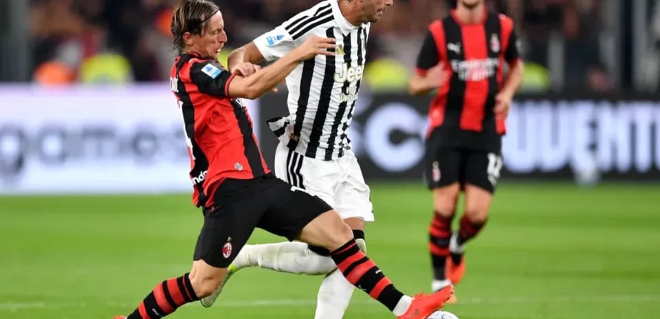 Jugador de AC Milan intenta quitar el balón a jugador de Juventus