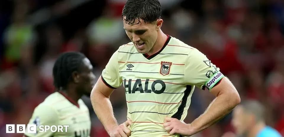 Jugador con camiseta de visitante, cabeza baja en el campo