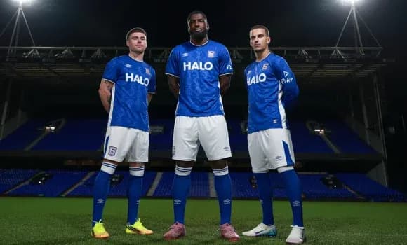 Tres jugadores posando en el campo con camisetas azules