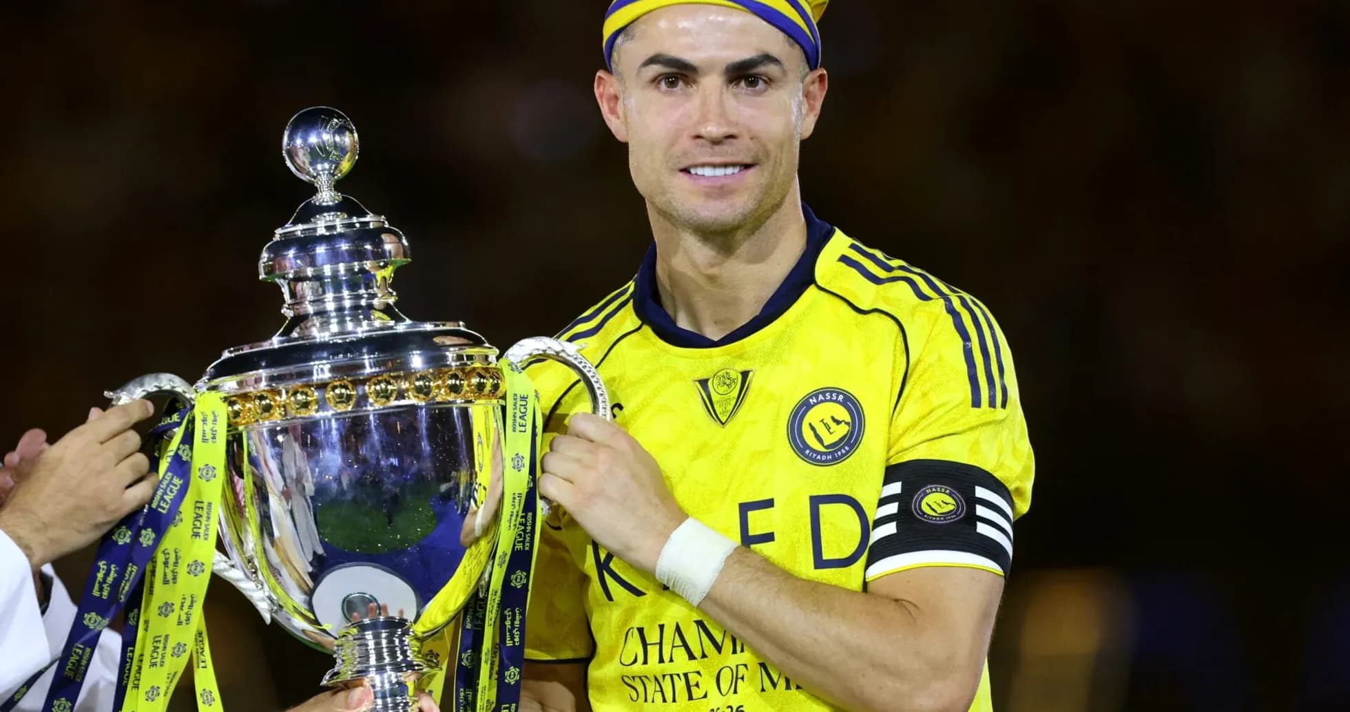 Jugador sosteniendo trofeo con camiseta amarilla