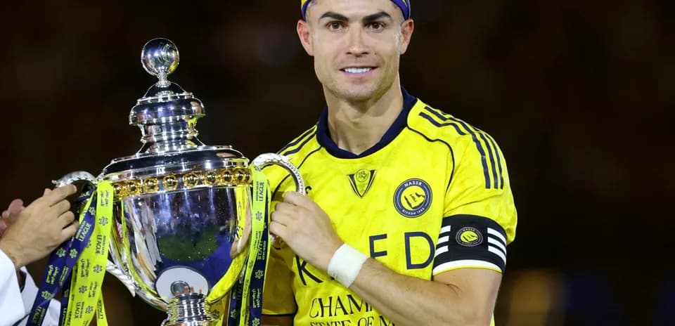 Jugador sosteniendo trofeo con camiseta amarilla