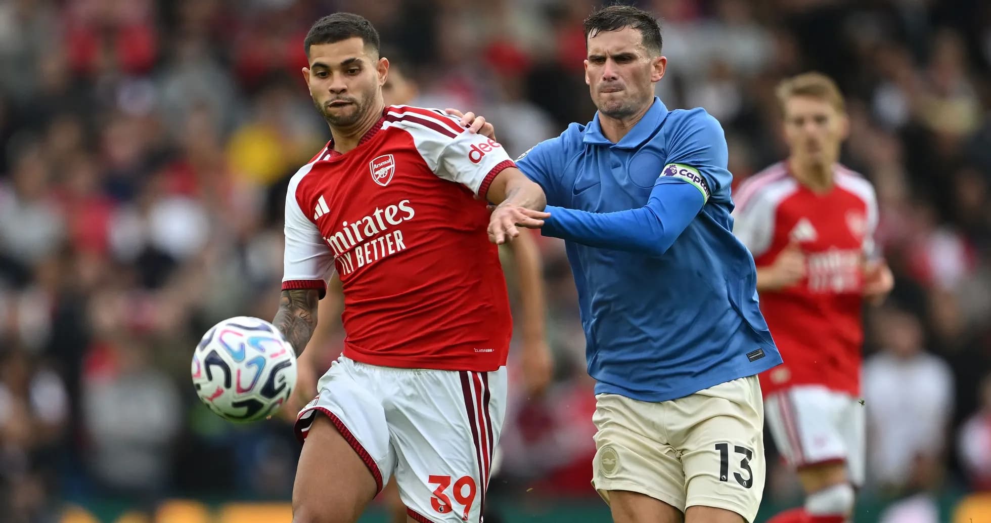 Jugador de Arsenal llevando el balón, rival persiguiéndolo