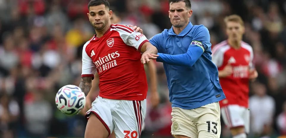 Jugador de Arsenal llevando el balón, rival persiguiéndolo