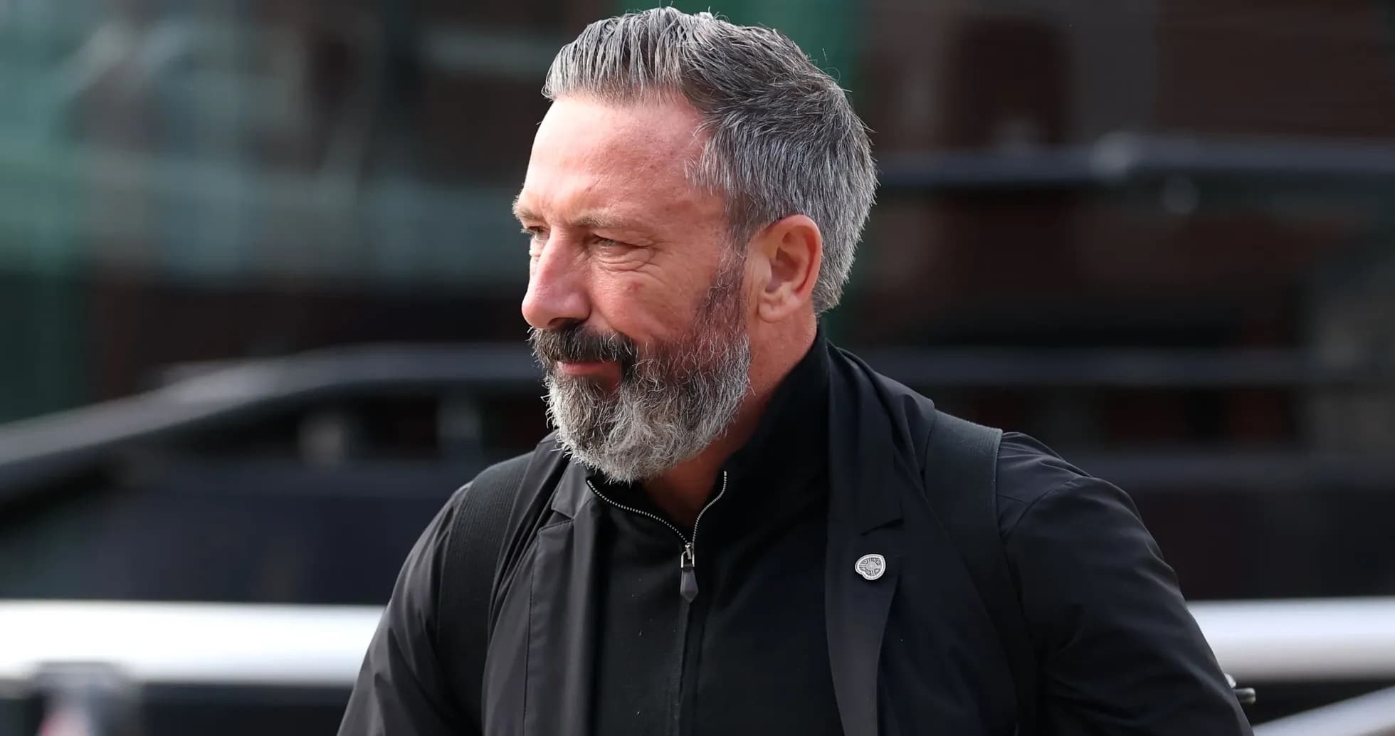 Hombre con barba gris caminando hacia el estadio