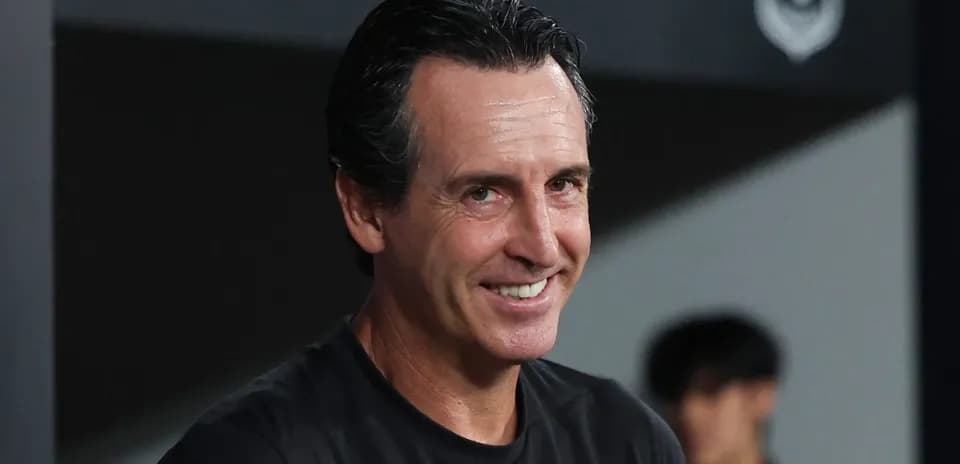 Entrenador sonriendo en la banca durante el partido