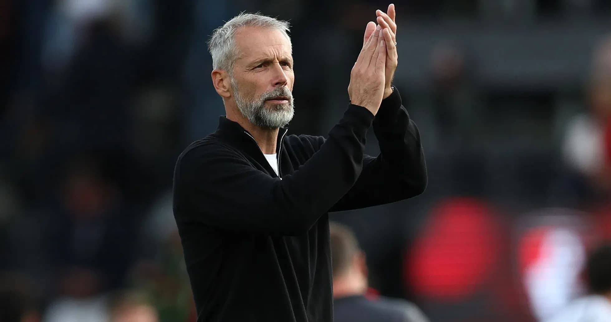 Entrenador aplaudiendo a los aficionados en el estadio