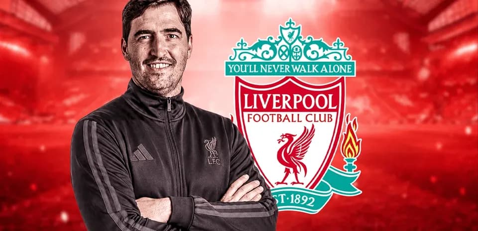 Entrenador de Liverpool posando frente al escudo