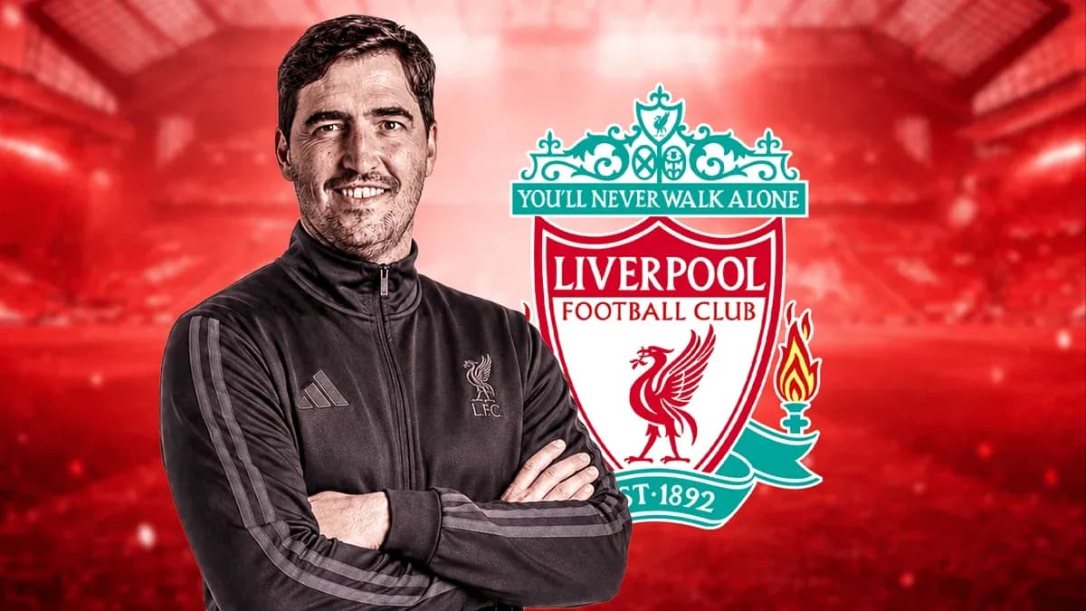 Entrenador de Liverpool posando frente al escudo