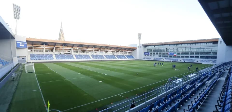 Estadio vacío con jugadores entrenando en el campo