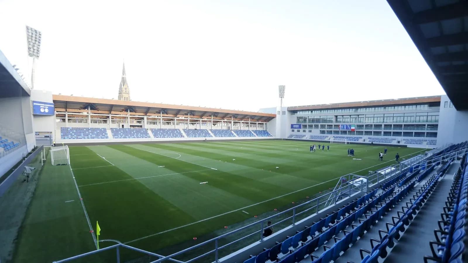 Estadio vacío con jugadores entrenando en el campo