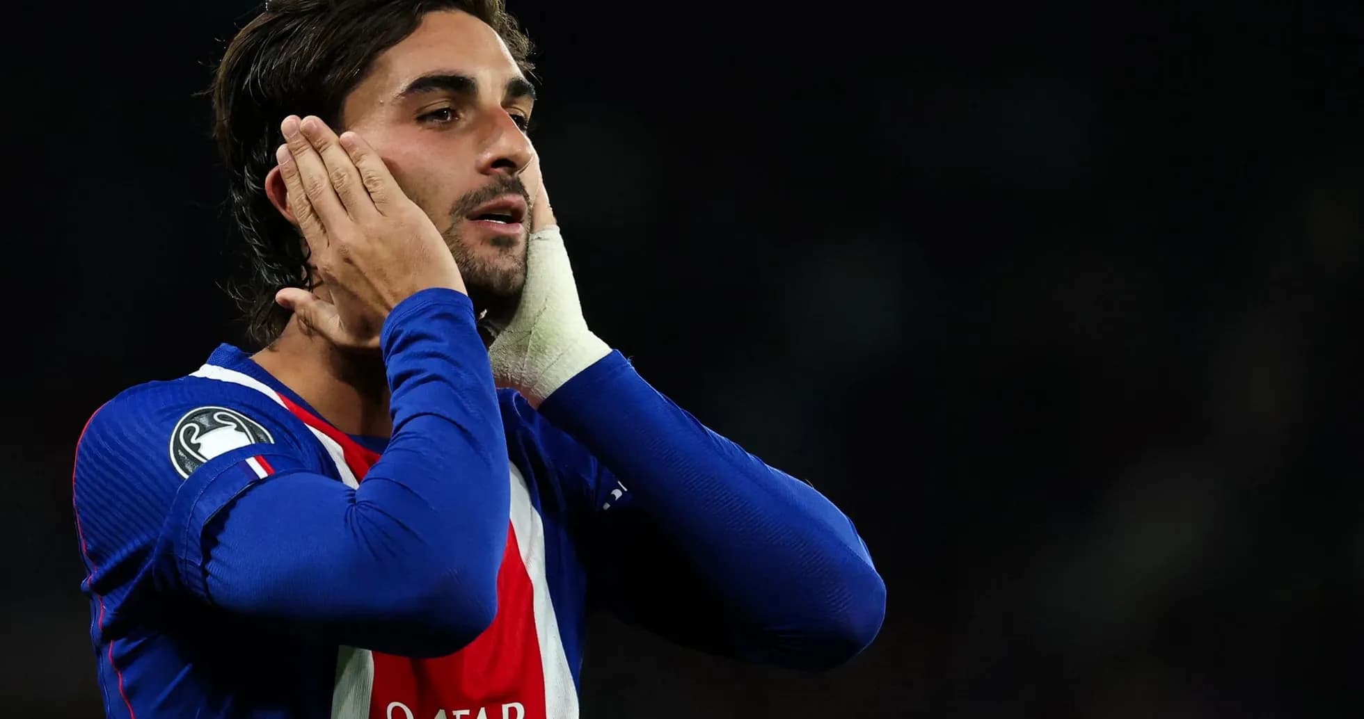 Jugador con camiseta azul tocándose la cabeza en el campo