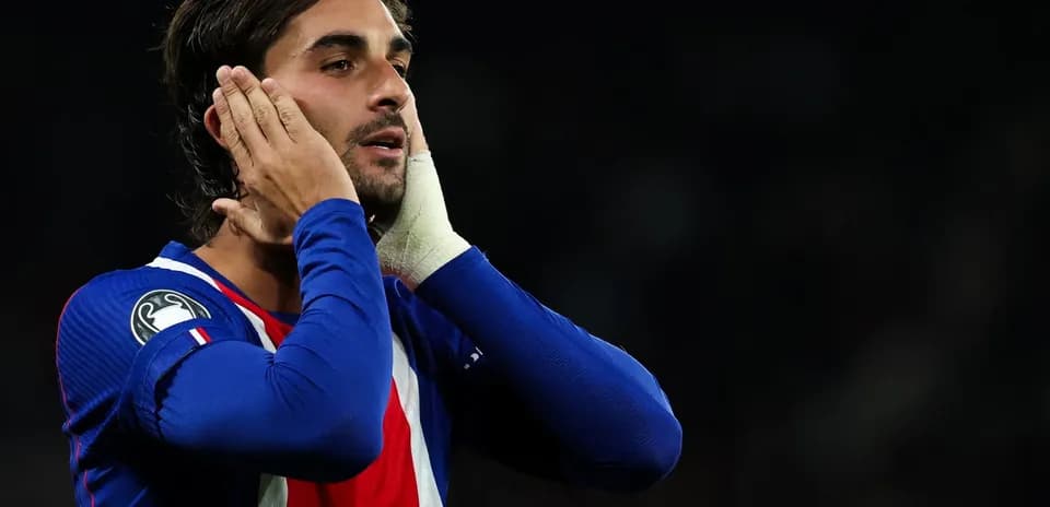 Jugador con camiseta azul tocándose la cabeza en el campo