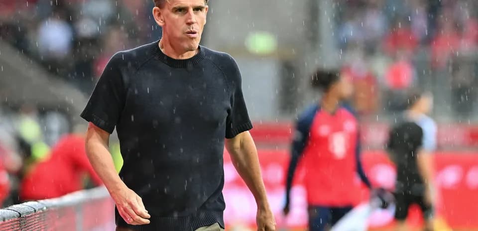 Entrenador caminando bajo la lluvia en el campo