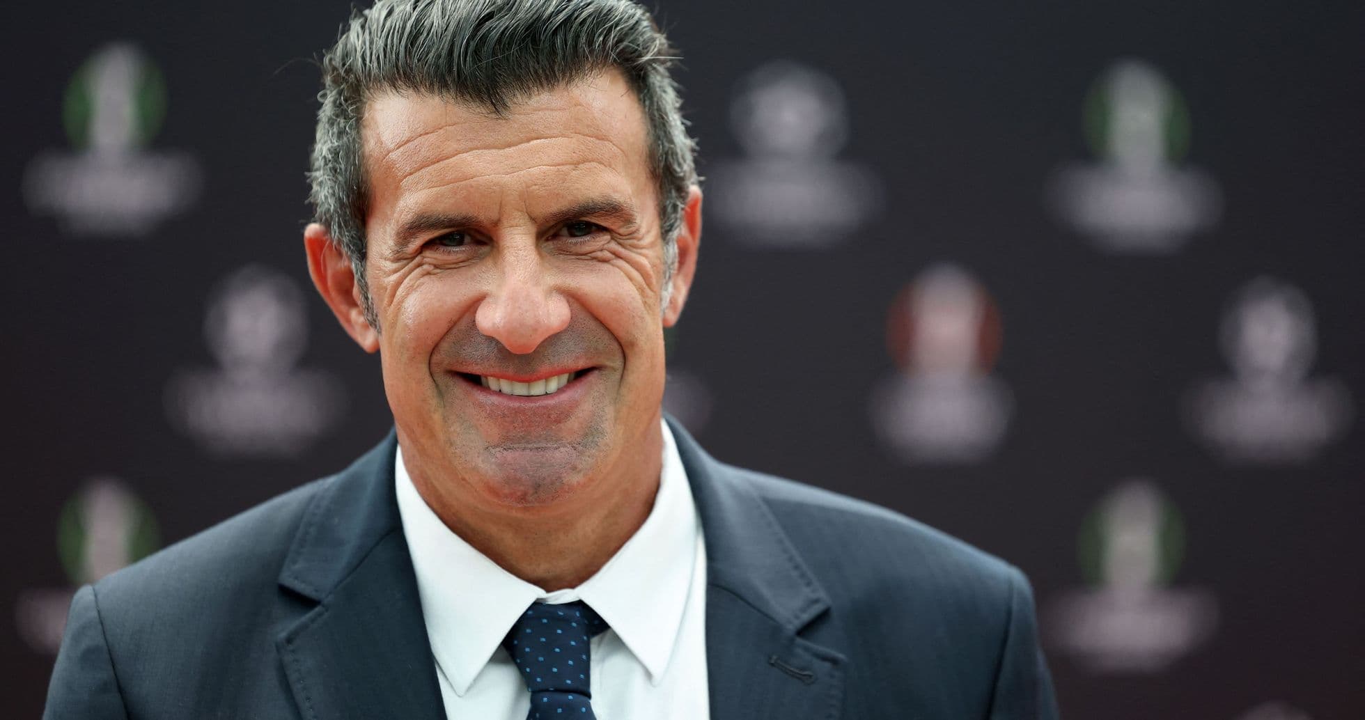 Hombre sonriendo en evento deportivo con fondo oscuro