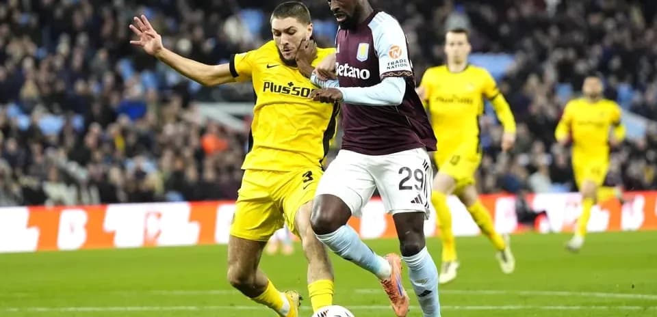 Jugador de Aston Villa driblando mientras es marcado