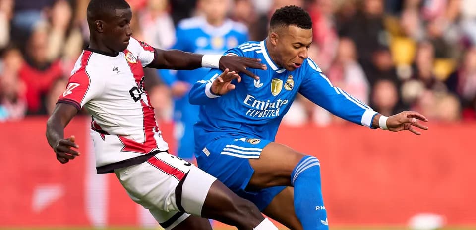 Jugador de Real Madrid siendo derribado por oponente