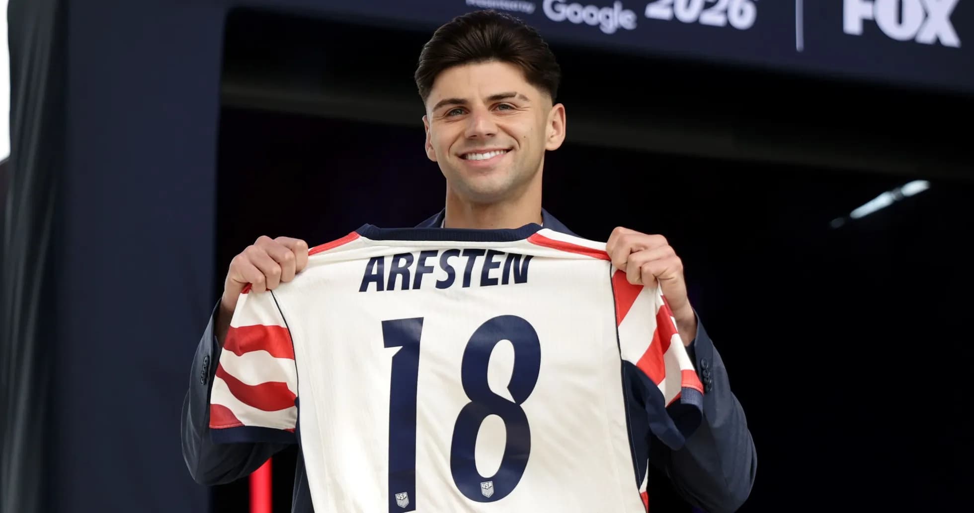 Jugador sosteniendo camiseta con nombre Arfsten y número 18