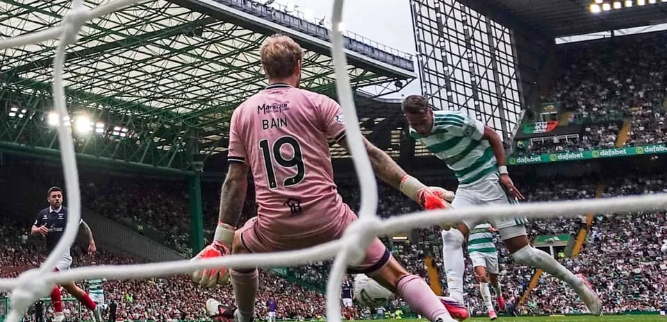 Jugador de Celtic disparando mientras el portero Bain se prepara