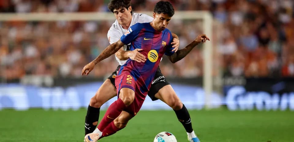 Jugador del Barcelona siendo marcado por rival