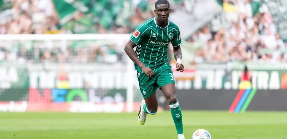 Jugador corriendo con balón en el campo de fútbol