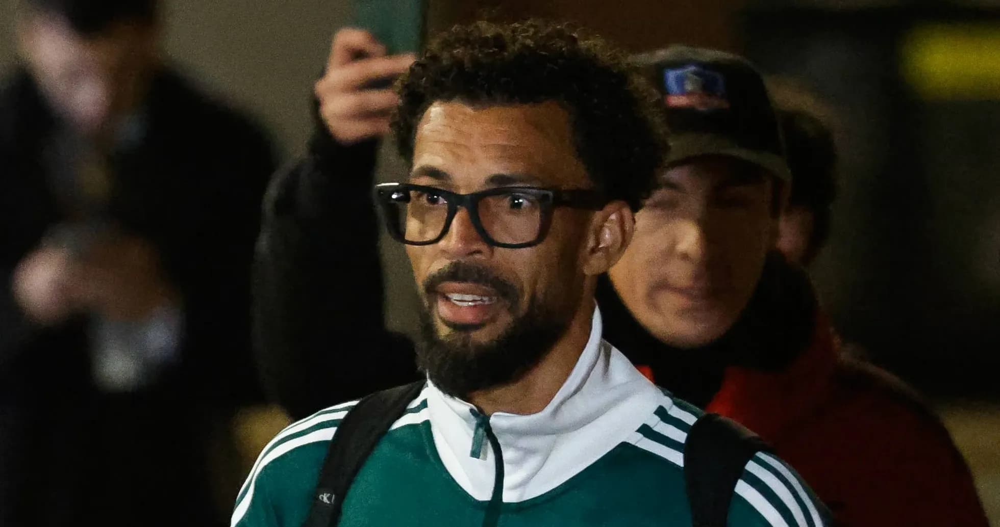 Jugador saliendo con chaqueta verde y gafas
