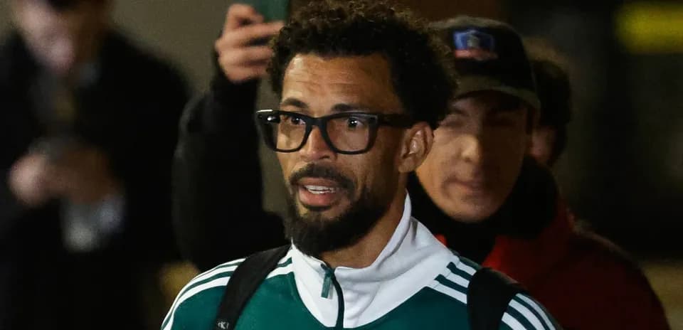 Jugador saliendo con chaqueta verde y gafas