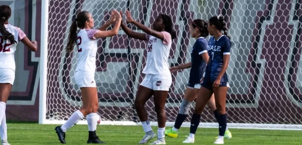Jugadoras celebrando un gol en el campo de fútbol
