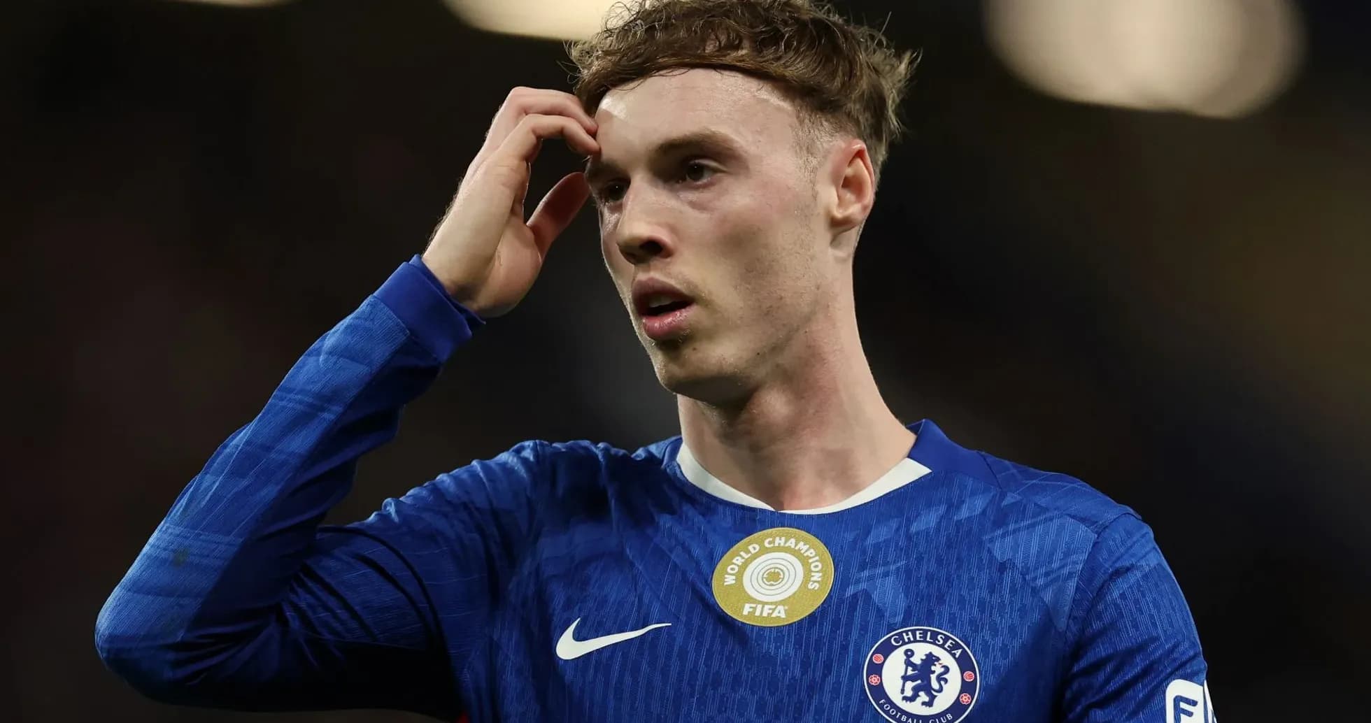 Jugador de Chelsea con camiseta azul tocándose la cabeza