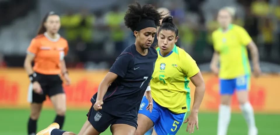 Jugadora de EE. UU. driblando ante rival de Brasil