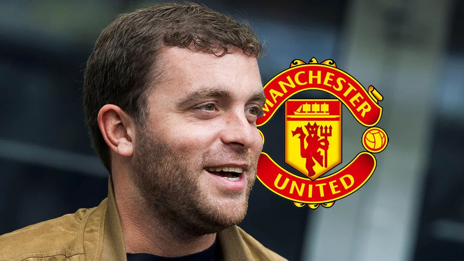 Hombre sonriendo frente al logo de Manchester United