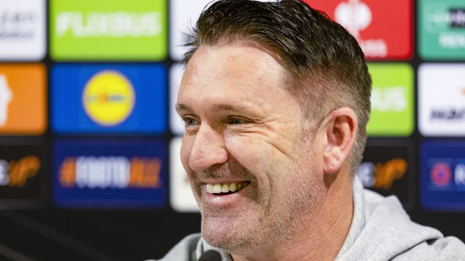 Entrenador sonriente en conferencia de prensa