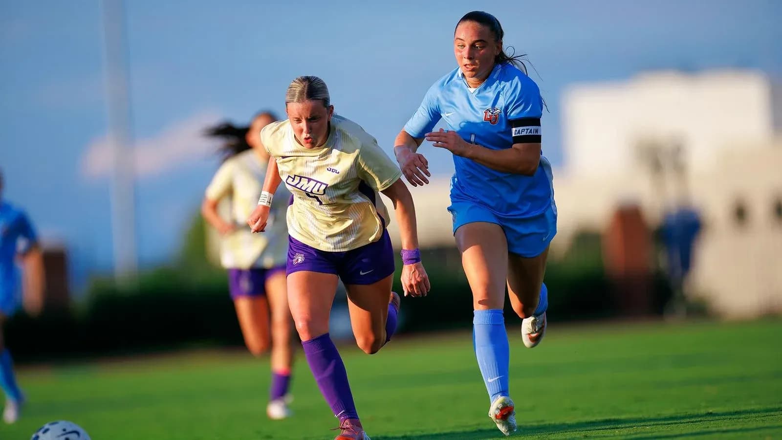 Jugadoras corriendo tras el balón en el campo