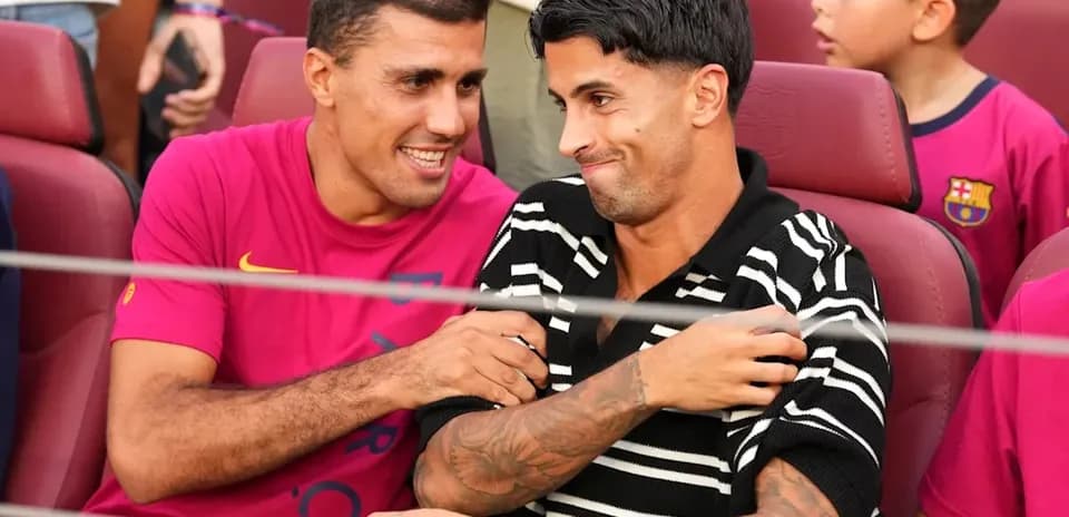 Dos jugadores sentados sonriendo en el estadio