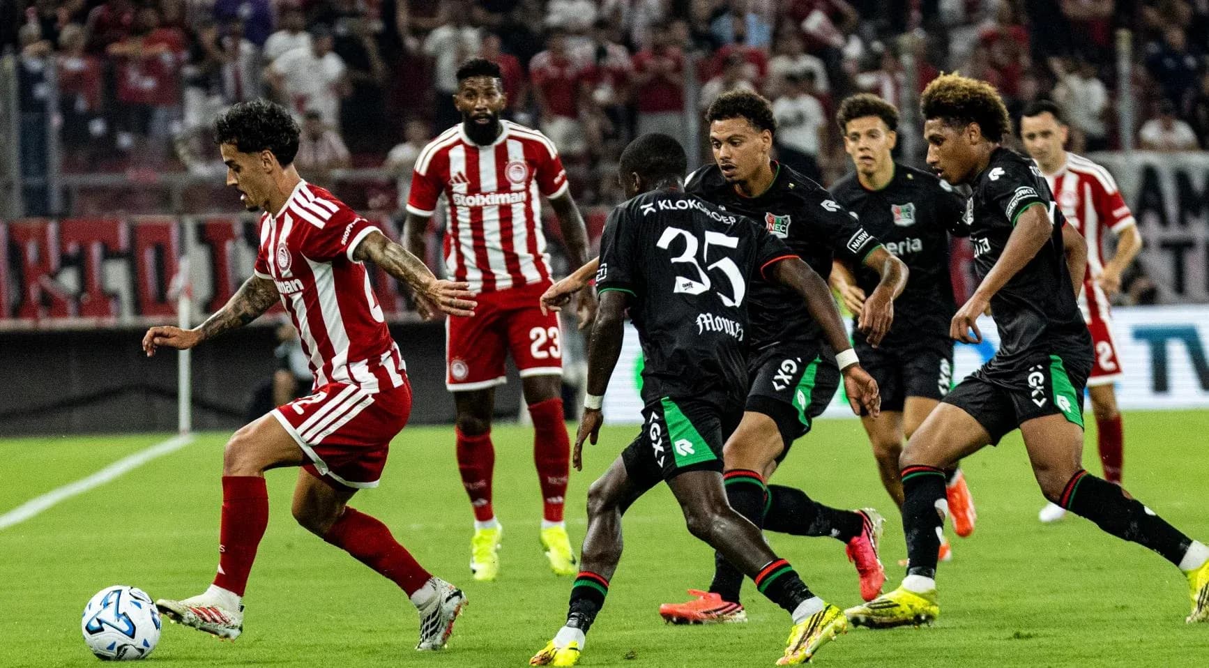 Jugador de Olympiakos esquivando a defensores de NEC Jugador de Olympiakos esquivando a defensores de NEC