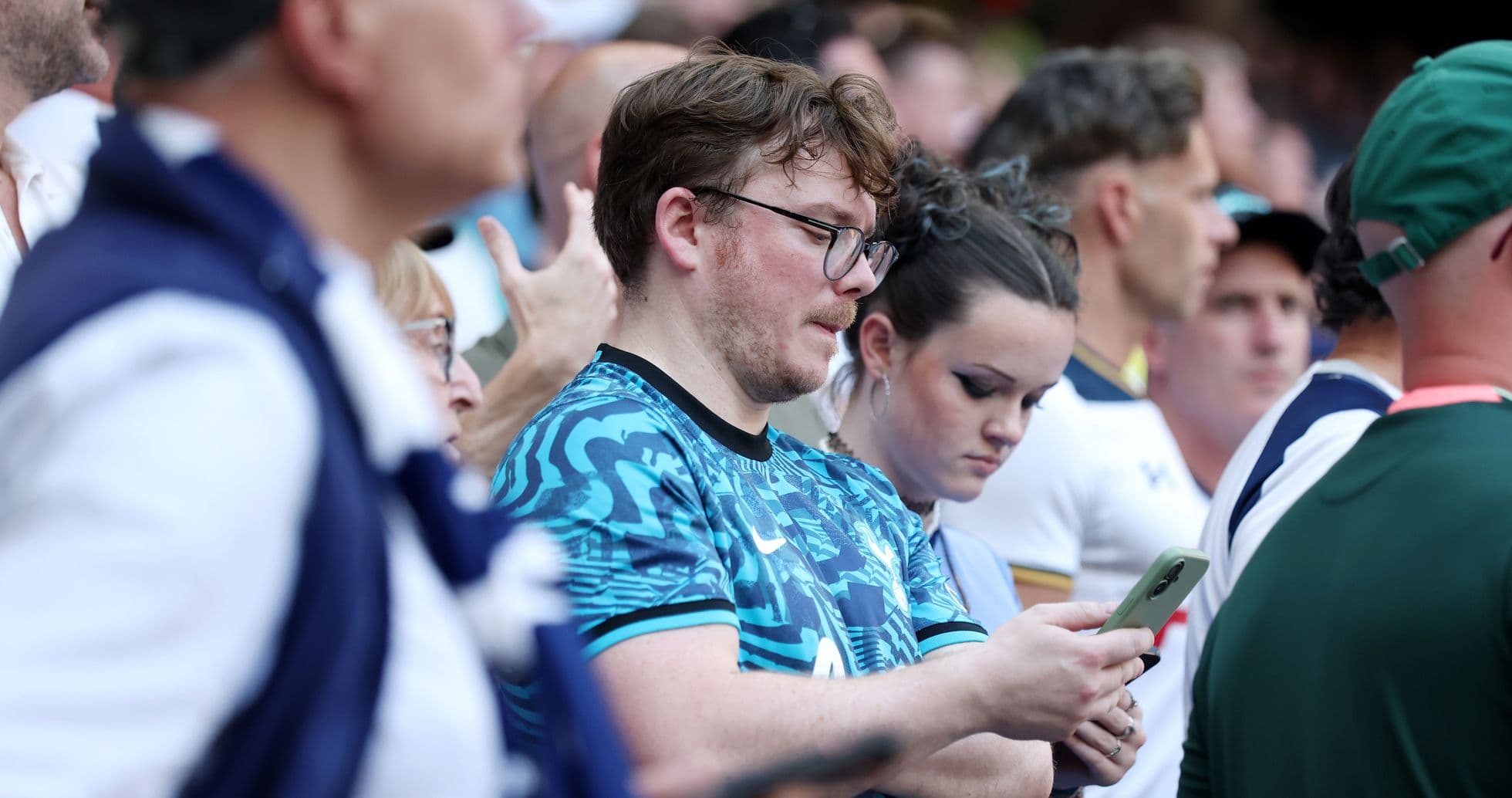 Espectadores en un evento deportivo revisando sus teléfonos Espectadores en un evento deportivo revisando sus teléfonos