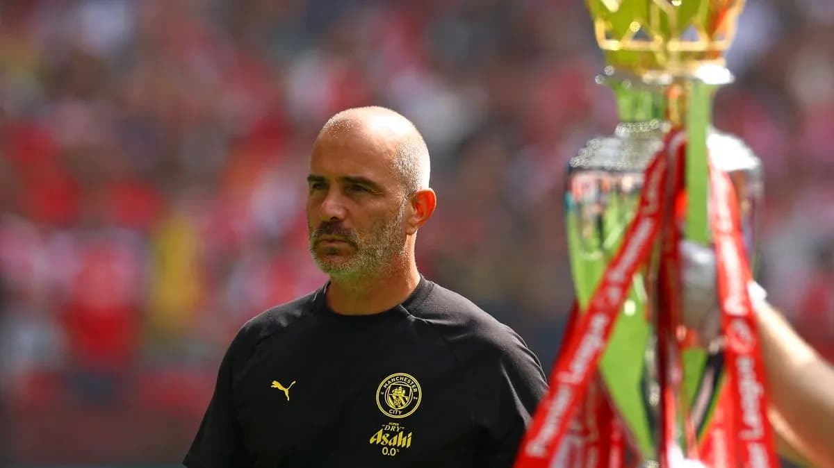 Entrenador de Manchester City junto a trofeo de campeonato Entrenador de Manchester City junto a trofeo de campeonato