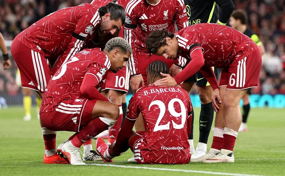 Jugadores de Liverpool consolando a compañero en el suelo Jugadores de Liverpool consolando a compañero en el suelo