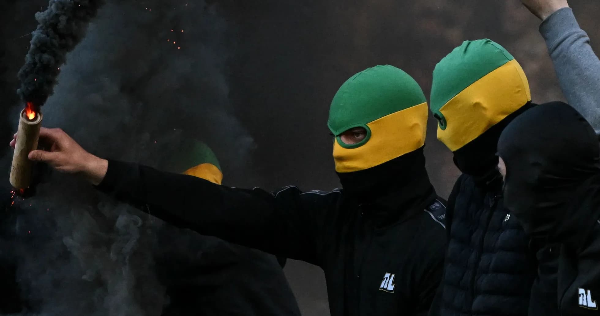 Grupo de personas con máscaras y bengala encendida Grupo de personas con máscaras y bengala encendida