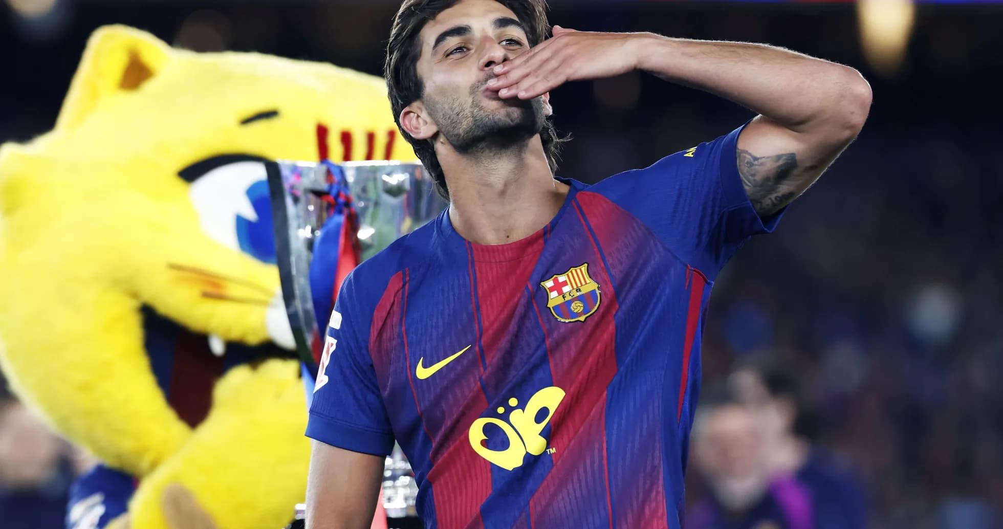 Jugador de Barcelona celebrando con trofeo y mascota Jugador de Barcelona celebrando con trofeo y mascota
