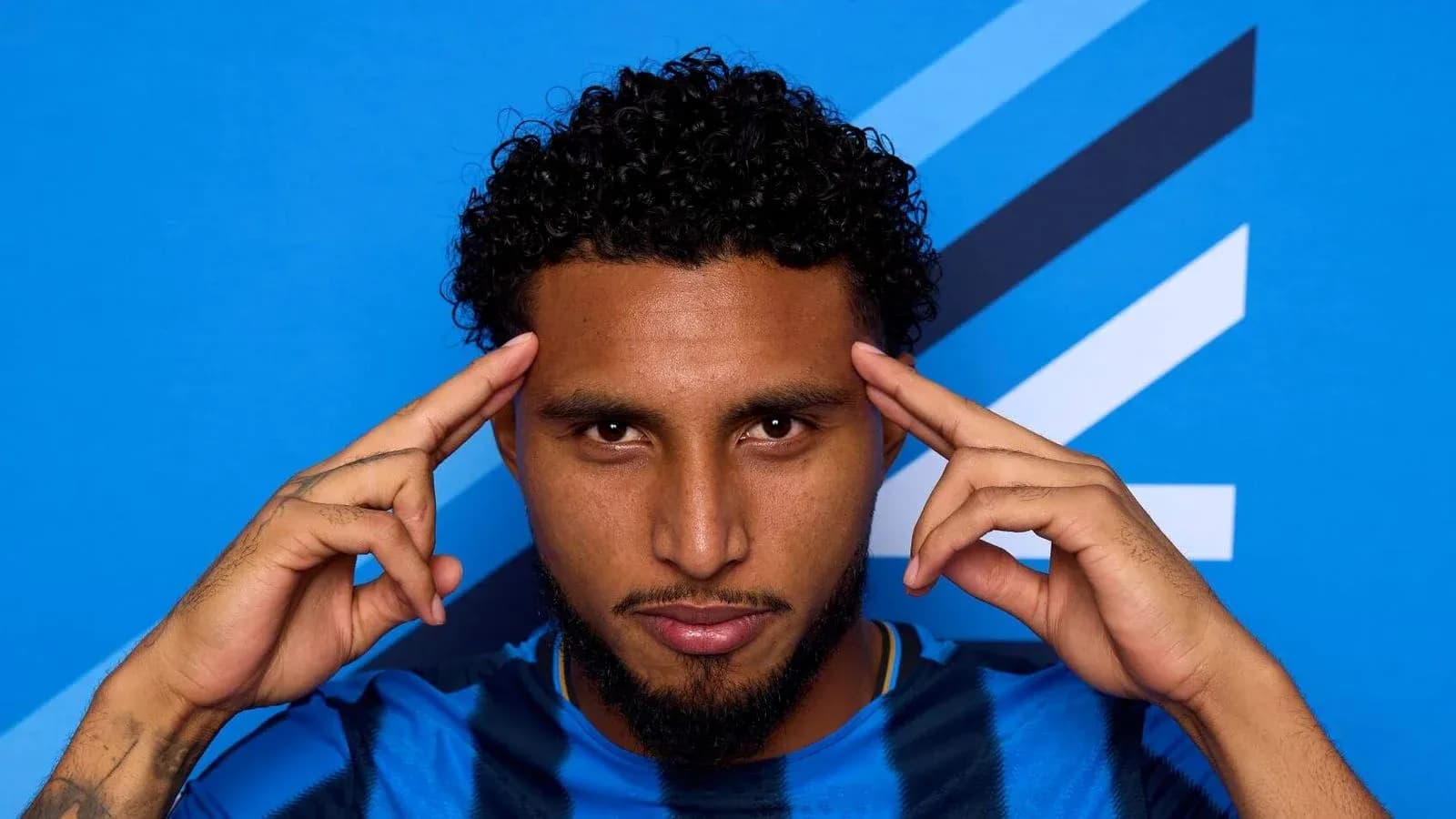 Jugador posando con fondo azul y camiseta a rayas Jugador posando con fondo azul y camiseta a rayas