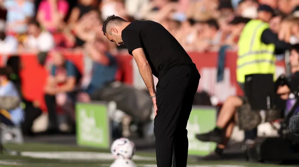 Entrenador agachado junto al balón en la línea de banda Entrenador agachado junto al balón en la línea de banda